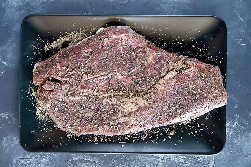 Horizontal image of seasoned uncooked beef on a tray.