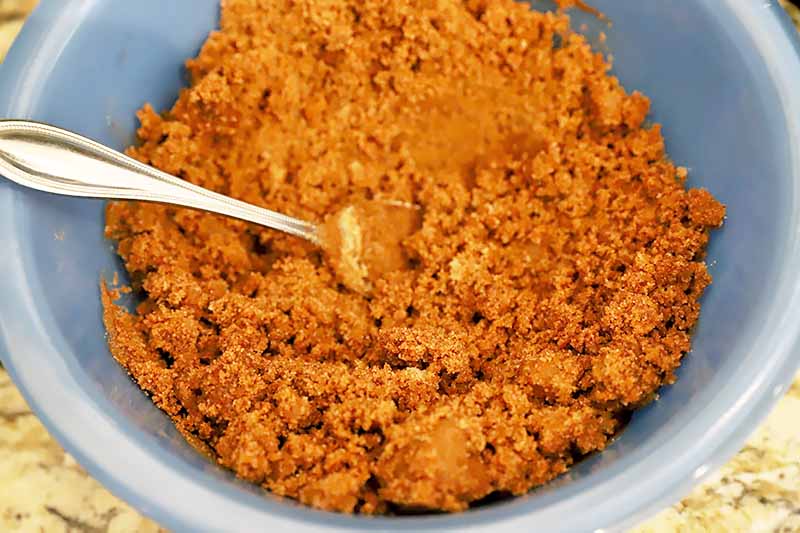 Horizontal image of a blue bowl with a cinnamon sugar filling and a metal spoon.