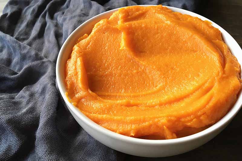 Horizontal image of a bowl with an orange smooth puree.