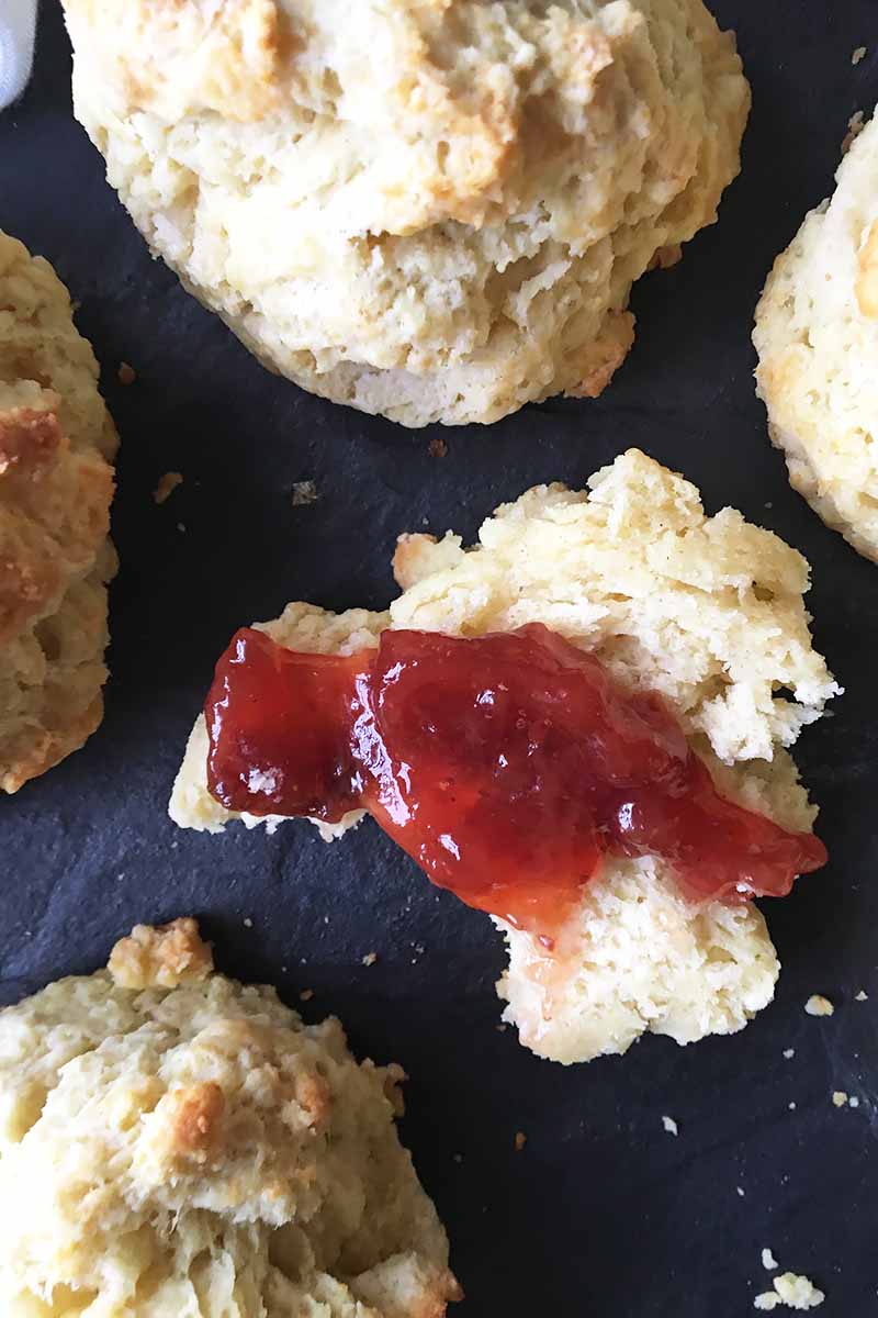 Vertical top-down image of biscuits, one cut in half spread with jam.