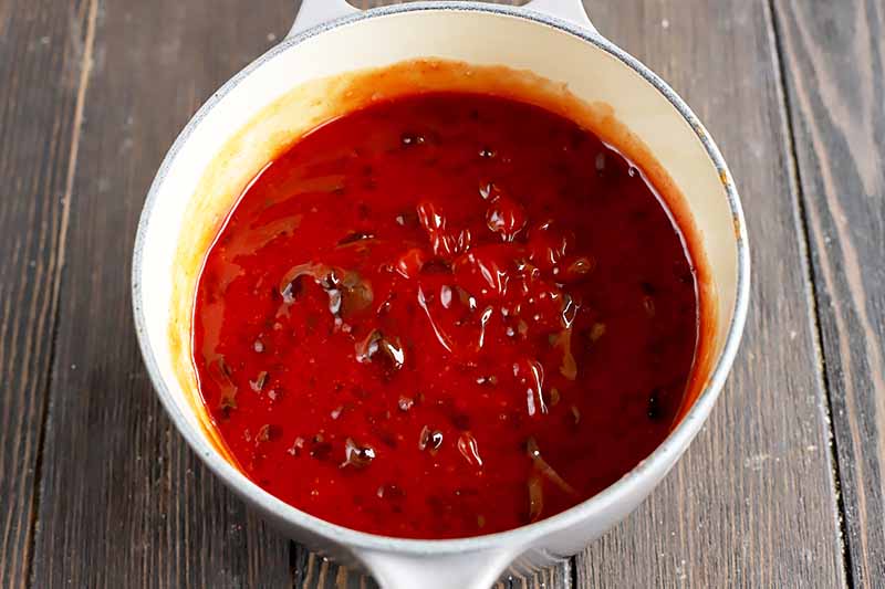 Horizontal image of a thick, red liquid mixture in a pot.