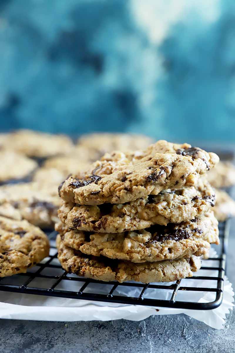 Vertical image of a stack of baked goods with chocolate chunks on a cooling rack.