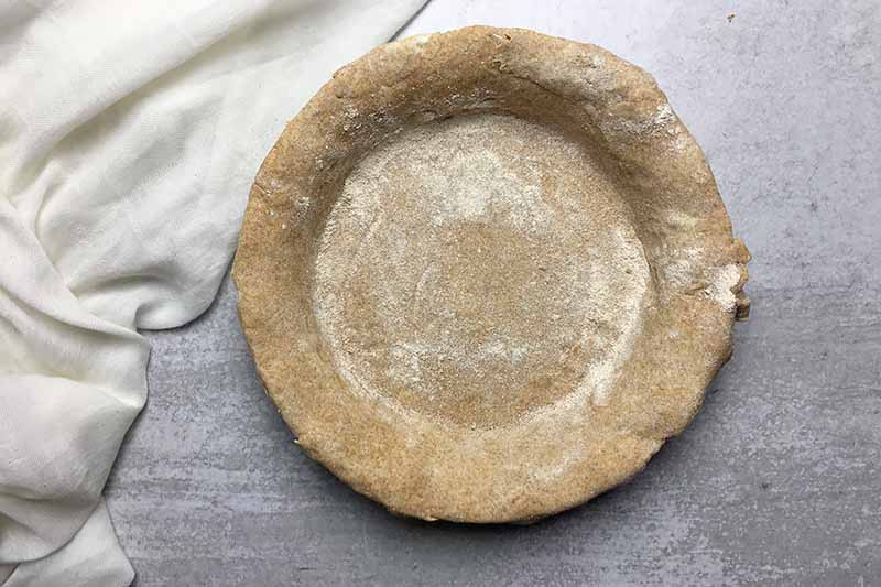 Horizontal image of a dough pressed into a pan.