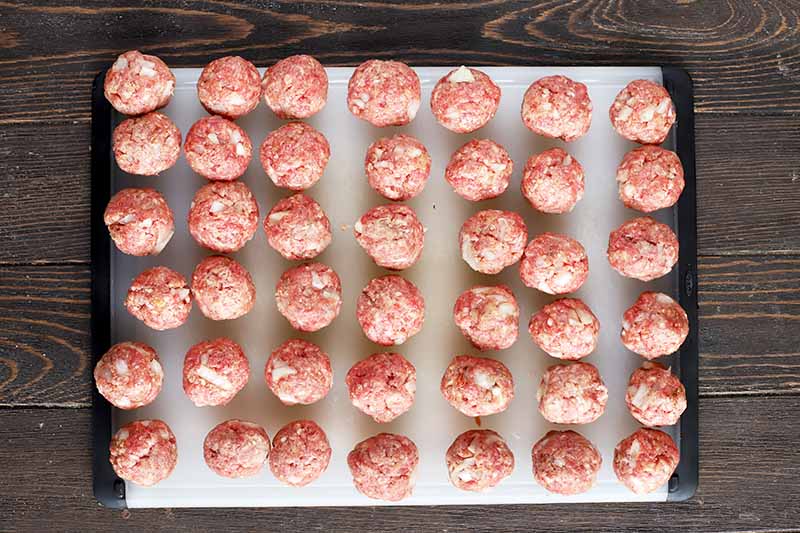 Horizontal image of raw ground beef formed in balls on a cutting board.