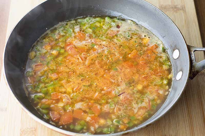 Horizontal image of a sofrito mixture cooking in a pan.