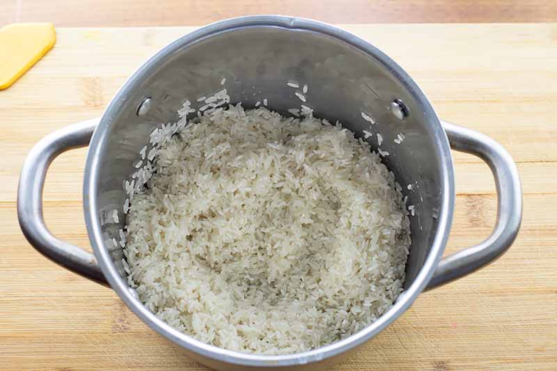 Horizontal image of a pot with cooked white rice.