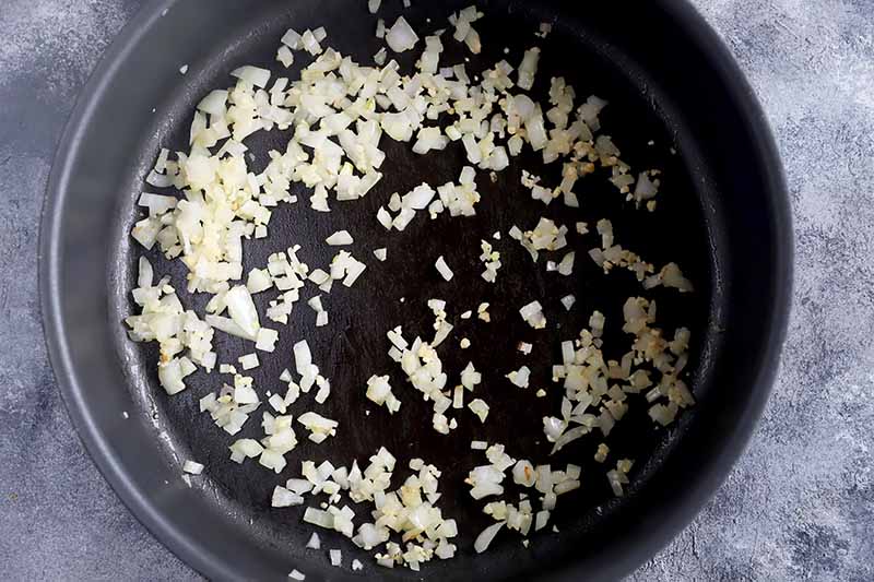 Horizontal image of cooking chopped garlic and onions in a pan.