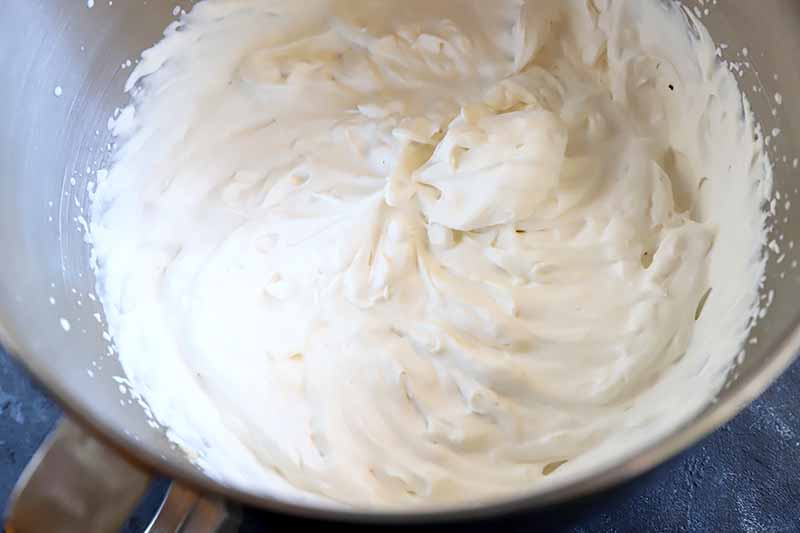 Horizontal image of whipped cream in a metal bowl.