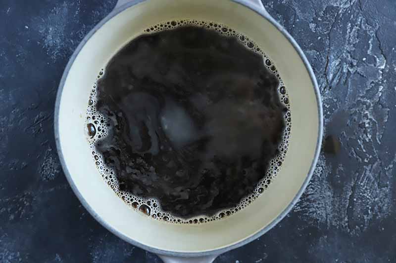Horizontal image of a pot boiling with a dark liquid.