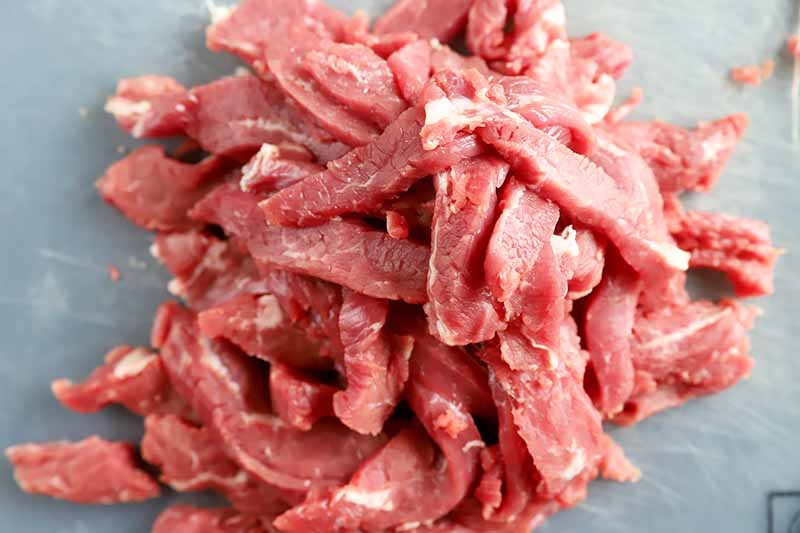 Horizontal image of thinly sliced raw beef.