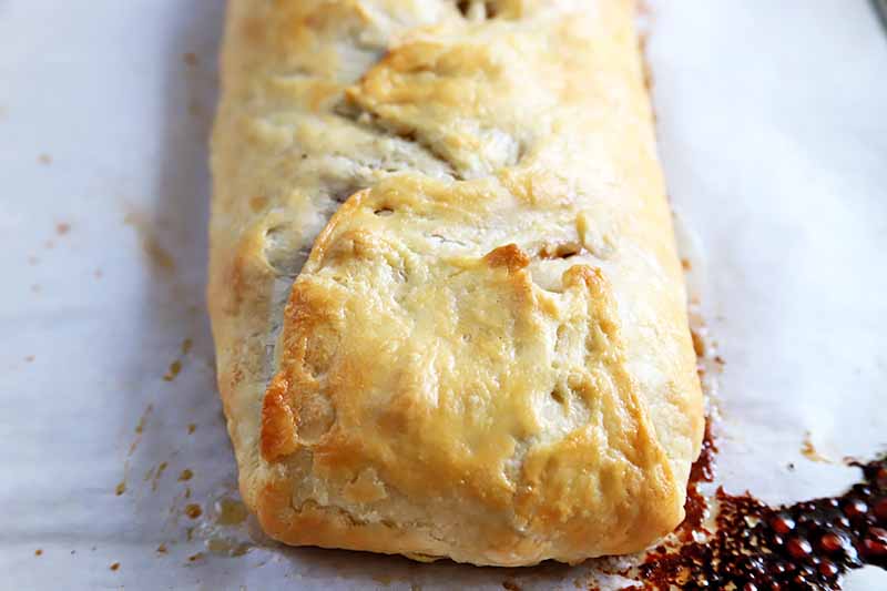 Horizontal image of a baked long, rectangular pastry on a baking sheet lined with parchment paper.