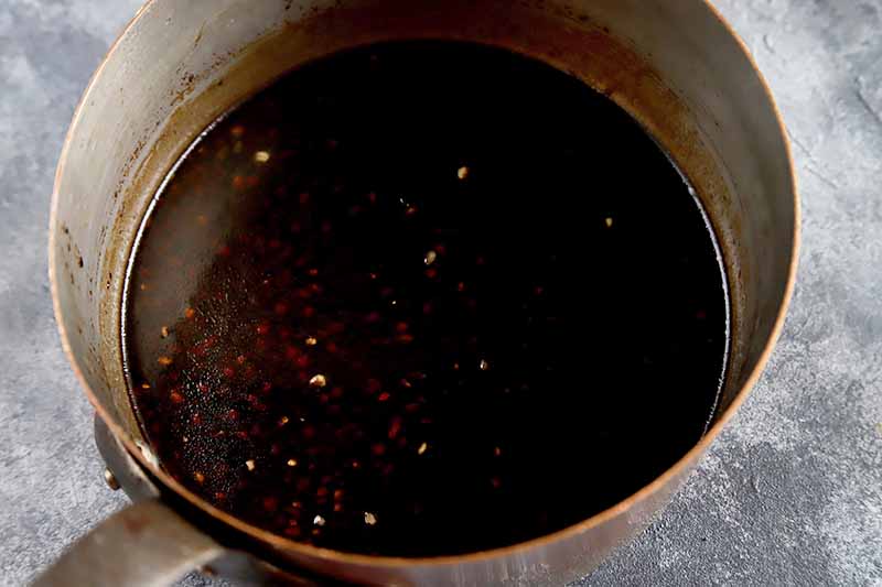 Horizontal image of a pot with a dark brown sauce.
