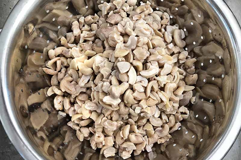 Horizontal image of cashews in a metal bowl.
