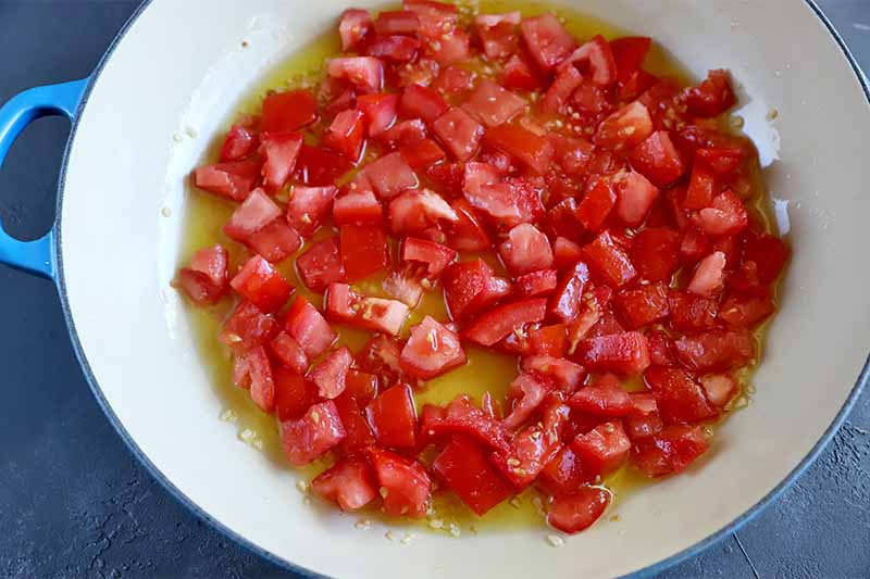 Horizontal image of a pan with chopped tomatoes and oil.