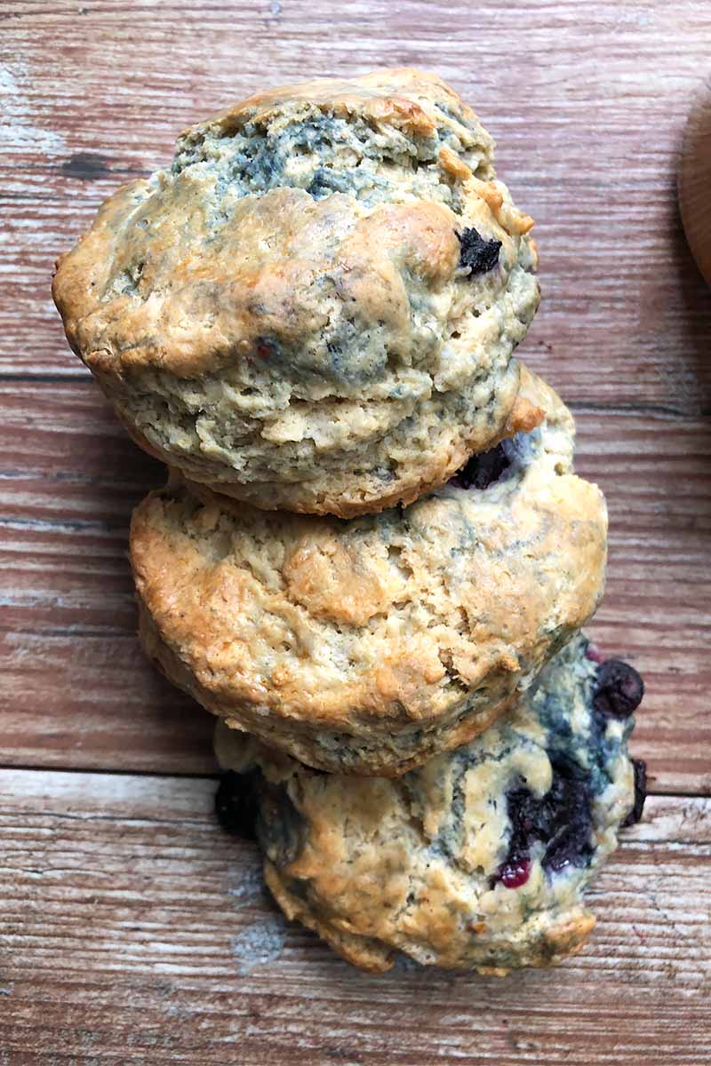 Vertical image of three shingled fruit scones on a wooden table.