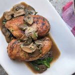 Horizontal image of a rectangular white plate with two chicken breasts in a mushroom sauce.