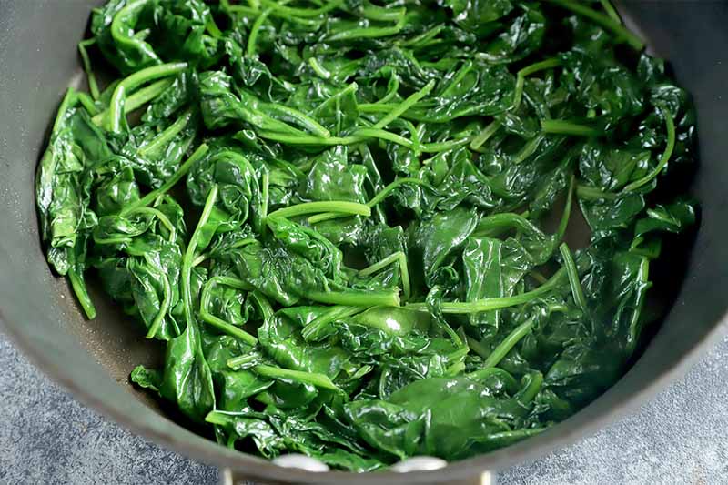 Horizontal image of cooked spinach in a pan.