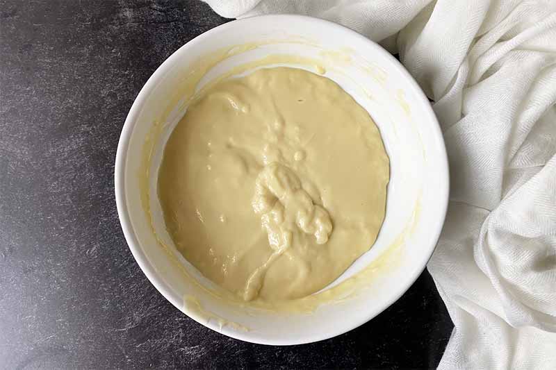 Horizontal image of a lightly set custard mixture in a white bowl.