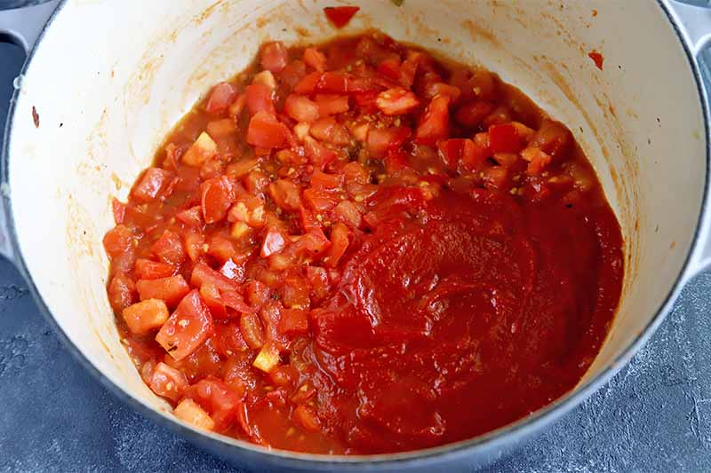 Horizontal image of cooking diced and stewed tomatoes in a pot.
