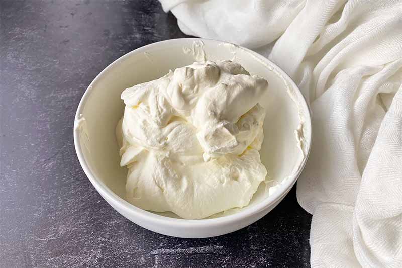 Horizontal image of a white bowl with whipped cream.