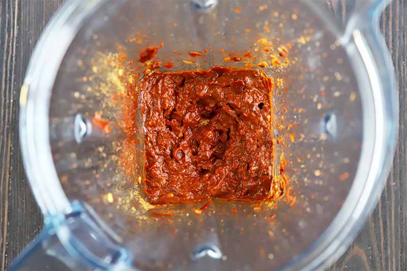 Horizontal image of a blender filled with a thick chili paste.