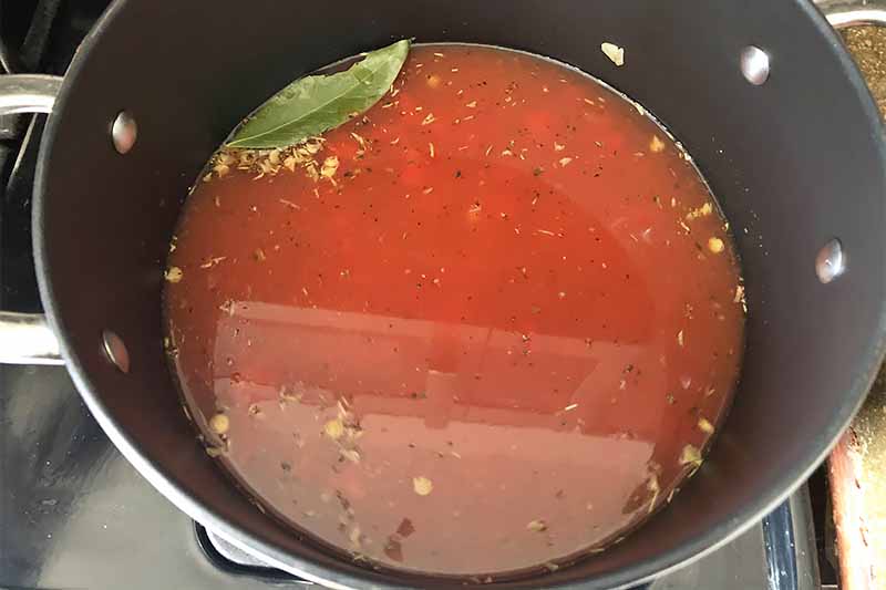 Horizontal image of a pot with a liquid red mixture with seasonings.