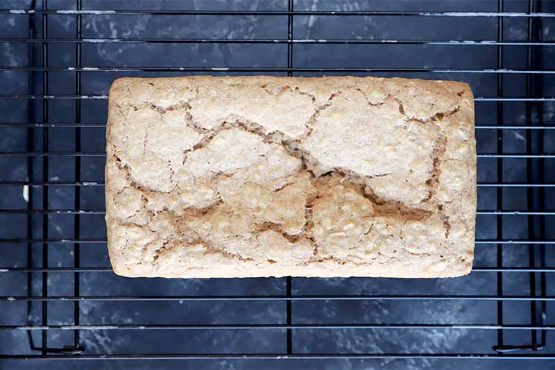 Horizontal image of a baked loaf on a cooling rack.
