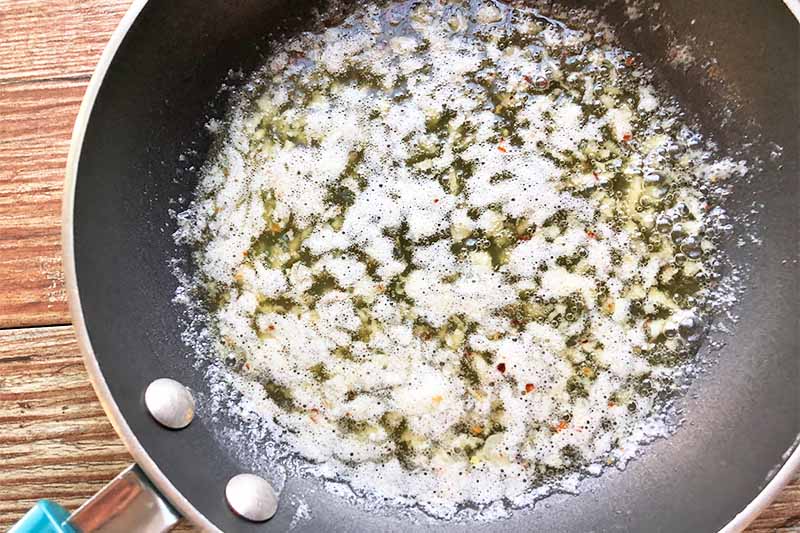 Horizontal image of cooking melted butter and aromatics in a pan.