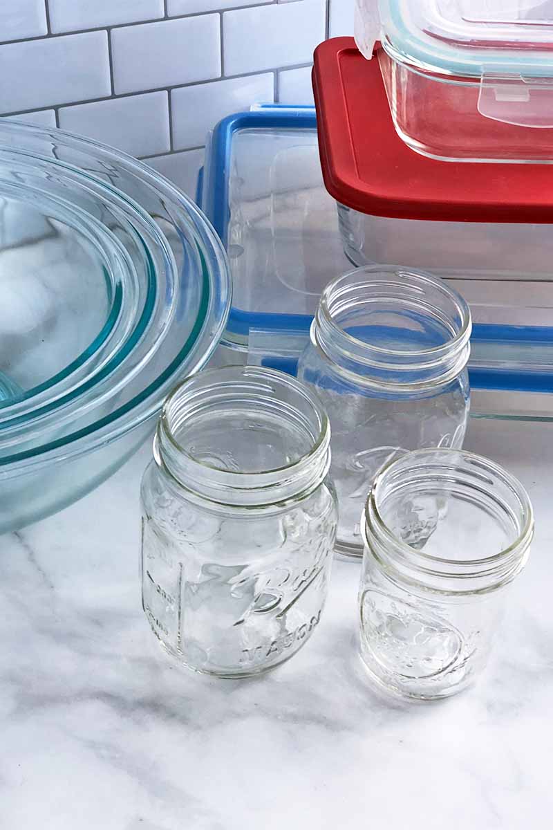 Vertical image of empty glass jars in various sizes, glass bowls in various sizes, and containers with lids.