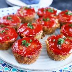 Horizontal image of small ground beef rounds baked and topped with ketchup on a blue plate.