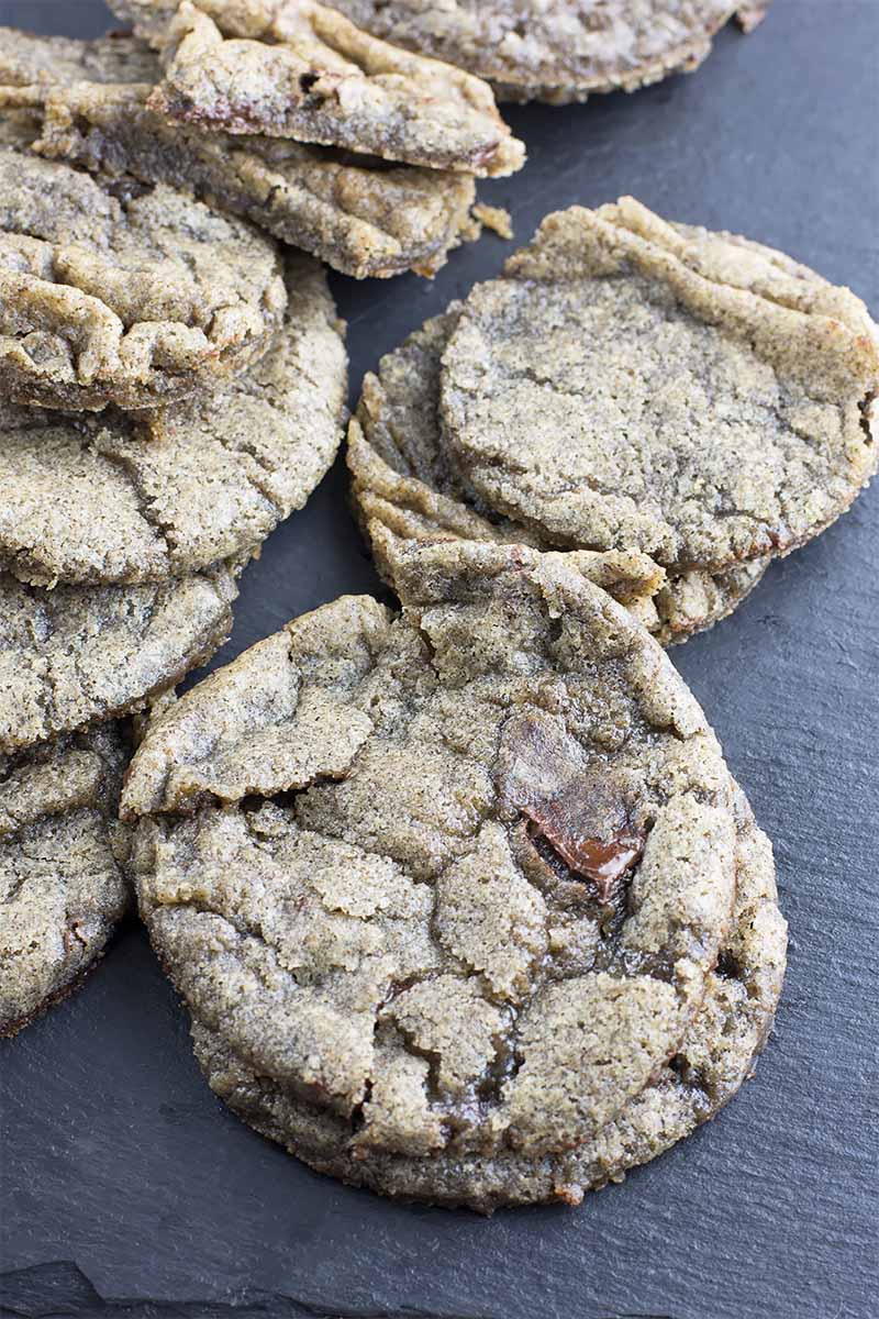 Vertical image of baked, slightly wrinkled cookies on a slate platter.