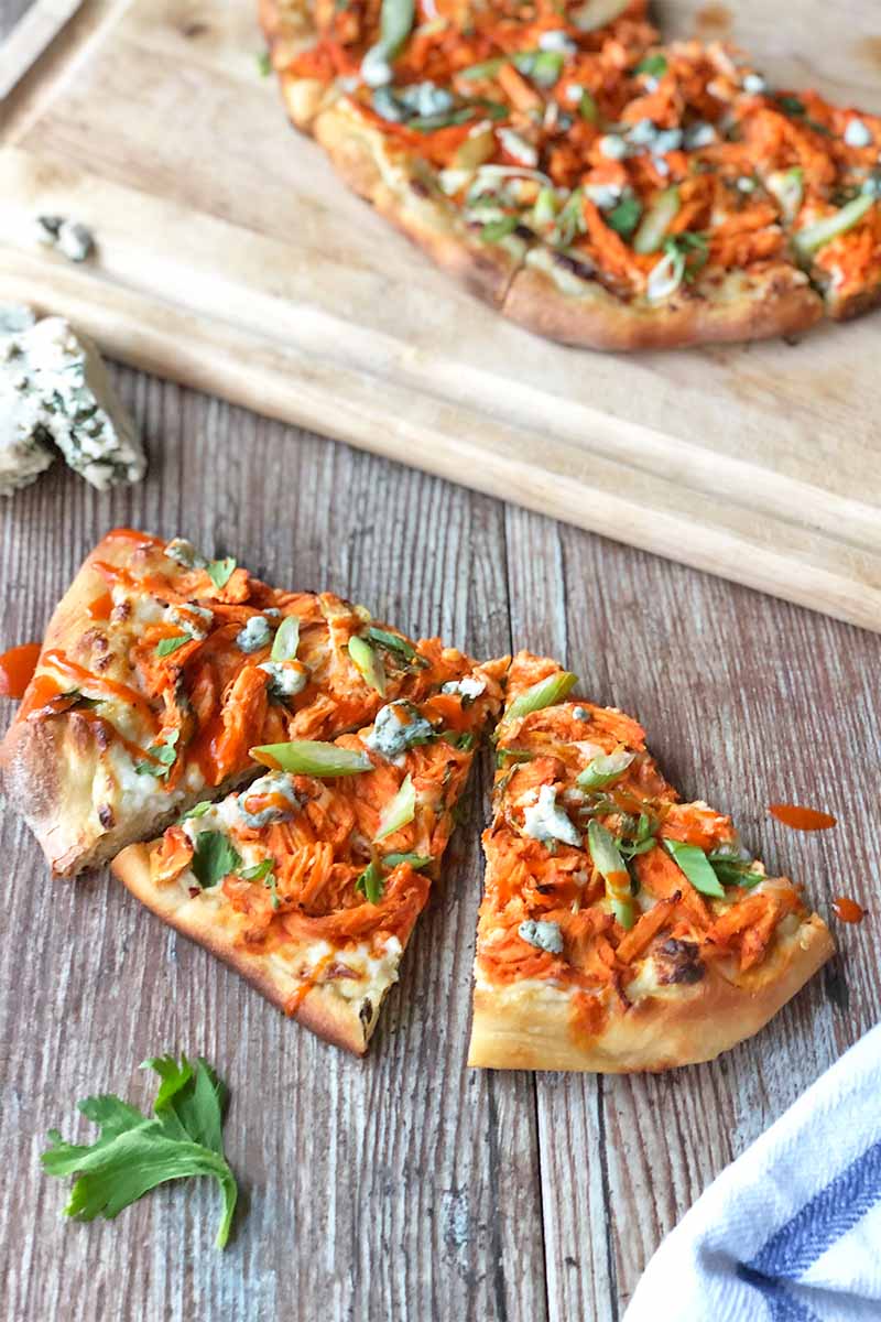 Vertical image of slices of a flatbread topped with shredded meat in a red sauce garnished with sliced green onions.