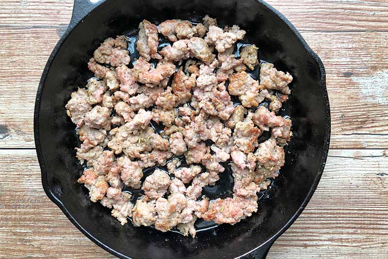 Horizontal image of a cast iron skillet with cooked crumbled meat.