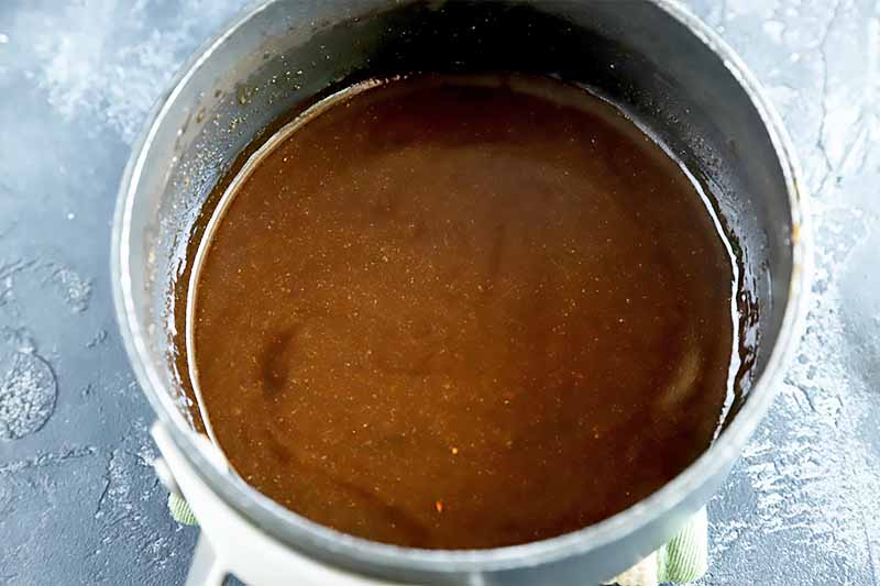 Horizontal image of a dark brown thick liquid in a pot.