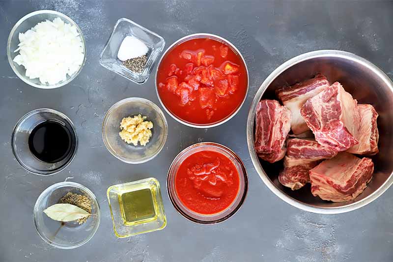 Horizontal image of raw meat in a bowl next to other small bowls with prepped dry and wet ingredients.