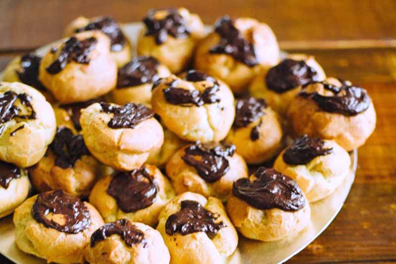 Horizontal image of a stack of small, round pastries topped with a dark brown glaze.