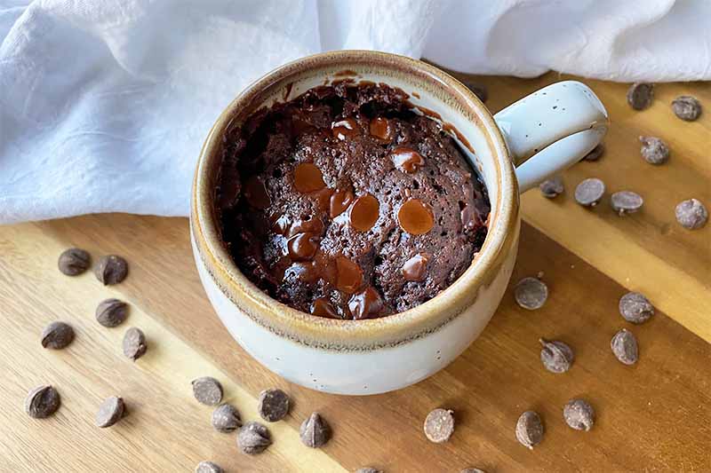 Horizontal image of chocolate dessert baked in a mug on a wooden board.