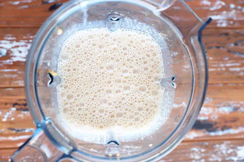 Horizontal image of a frothy, milky mixture in a blender.