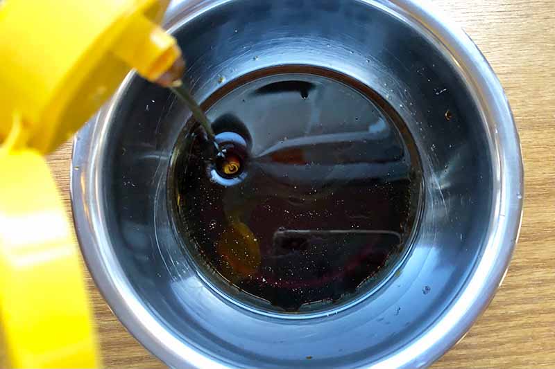 Horizontal image of a dark and thick brown sauce in a metal bowl.