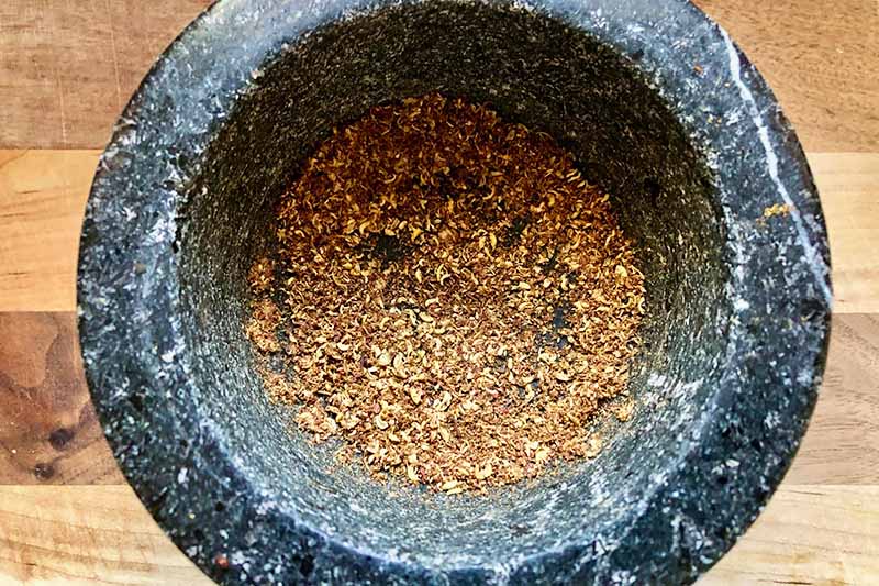 Horizontal image of ground peppercorns in a mortar.