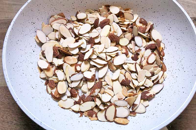 Horizontal image of toasted sliced almonds in a skillet.