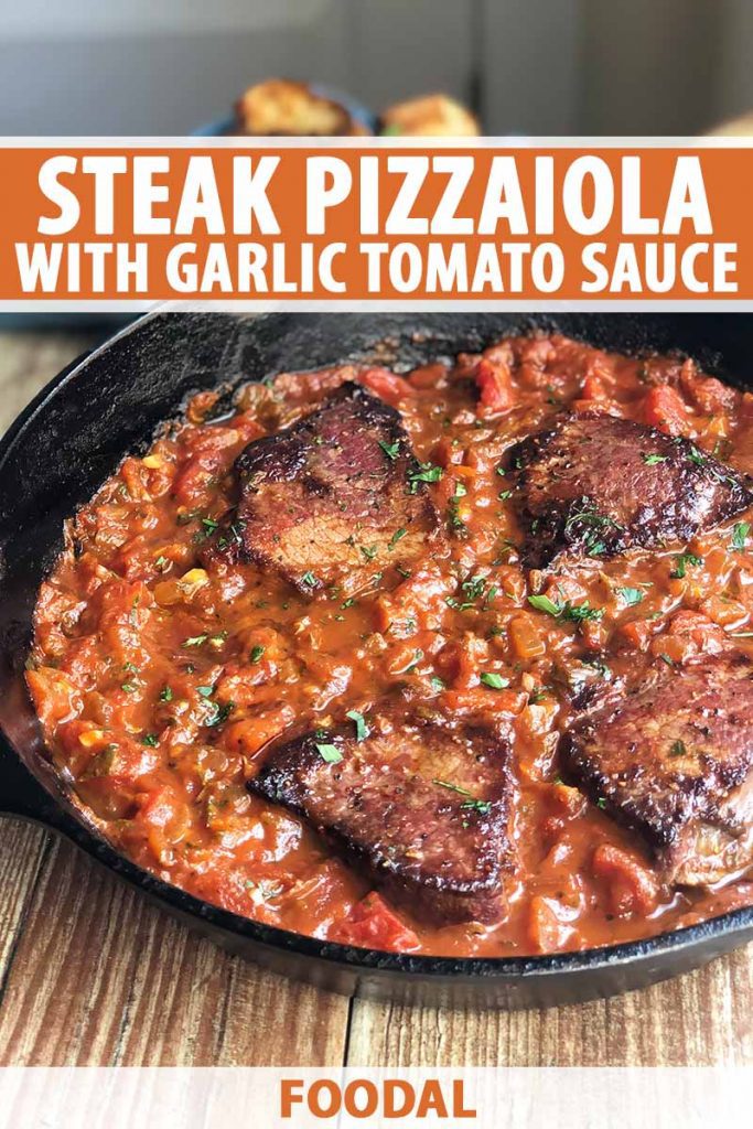 Vertical image of large pieces of seared beef in a tomato sauce in a cast iron skillet, with text on the top and bottom of the image.