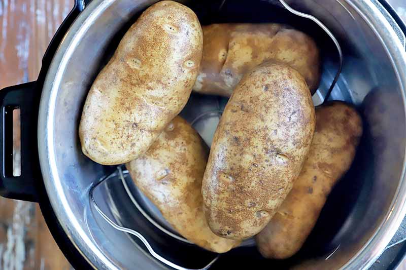 Horizontal image of a pile of whole, unpeeled potatoes in an Instant Pot.