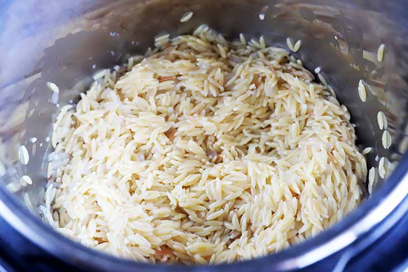 Horizontal image of tender orzo in a pot.