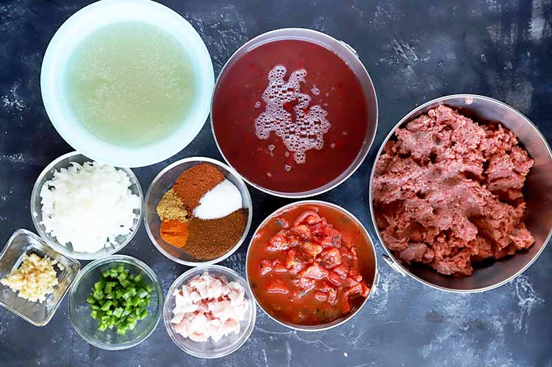 Horizontal image of prepped ingredients in bowls to make a beef stew.