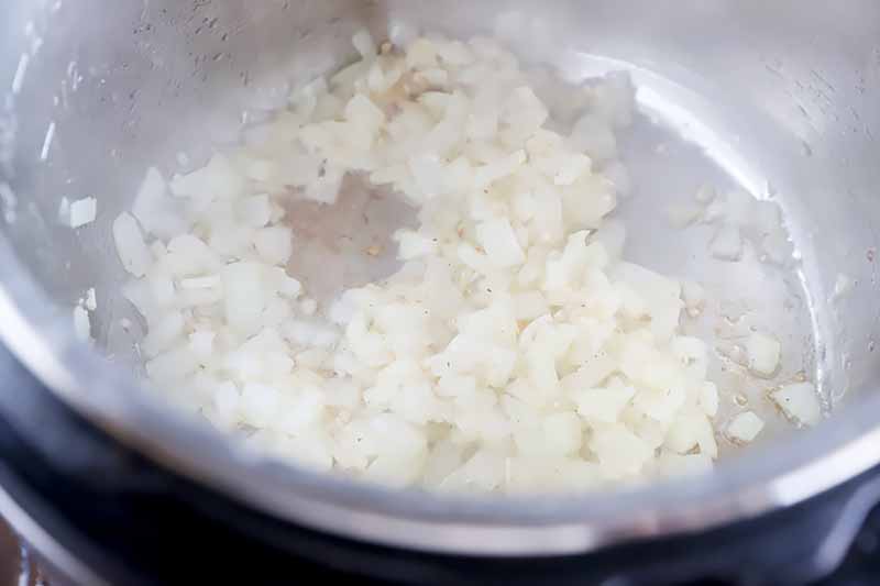 Horizontal image of browning chopped onions in a pot.