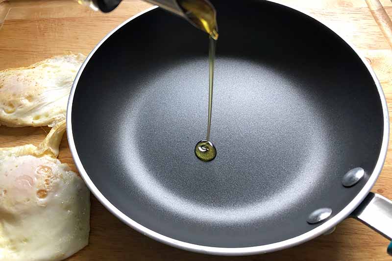 Horizontal image of pouring oil in an empty skillet.