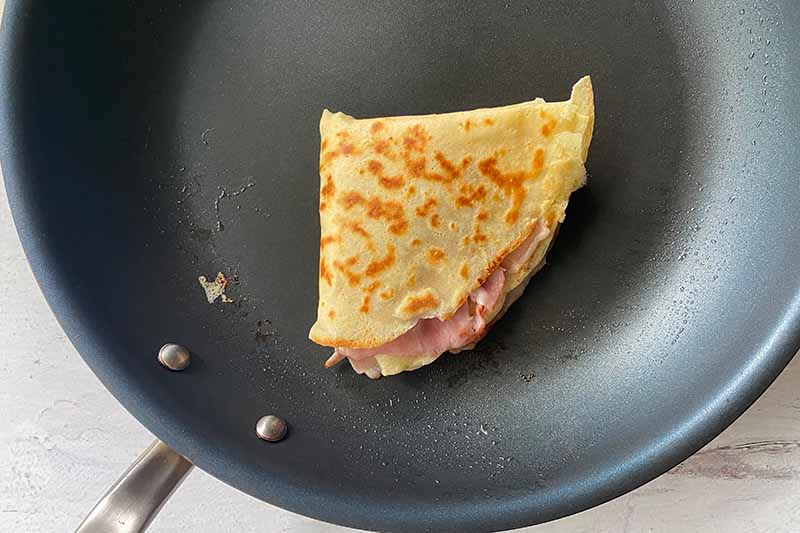 Horizontal image of a folded thin pancake in a skillet.