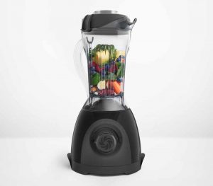 Horizontal image of a blender filled with pieces of fruit and vegetables.