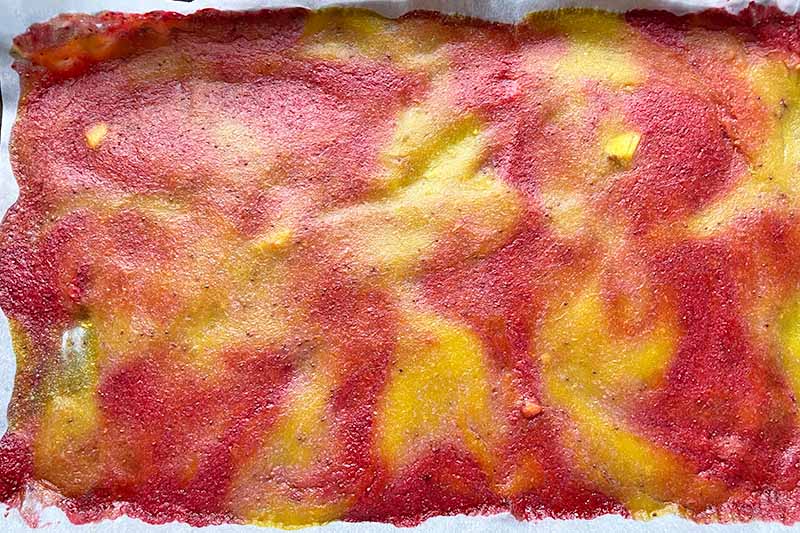 Horizontal image of a dried layer of marbled red and orange puree.